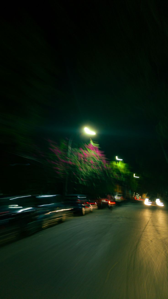 Motion blur night street light trails with purple bougainvillea