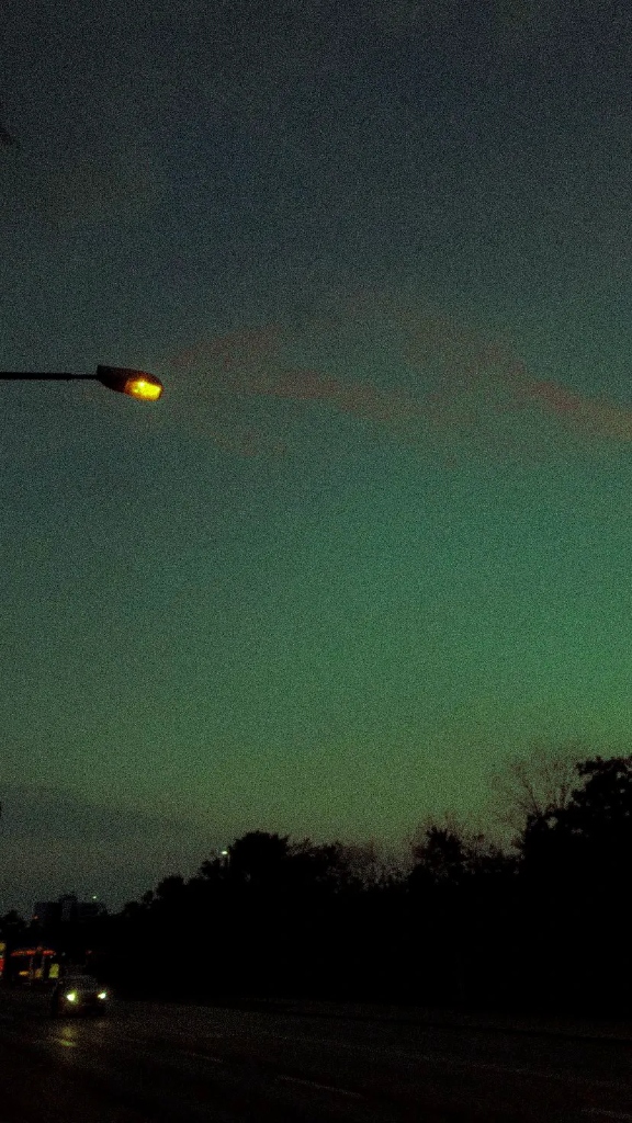 Moody grainy dusk sky with warm street lamp