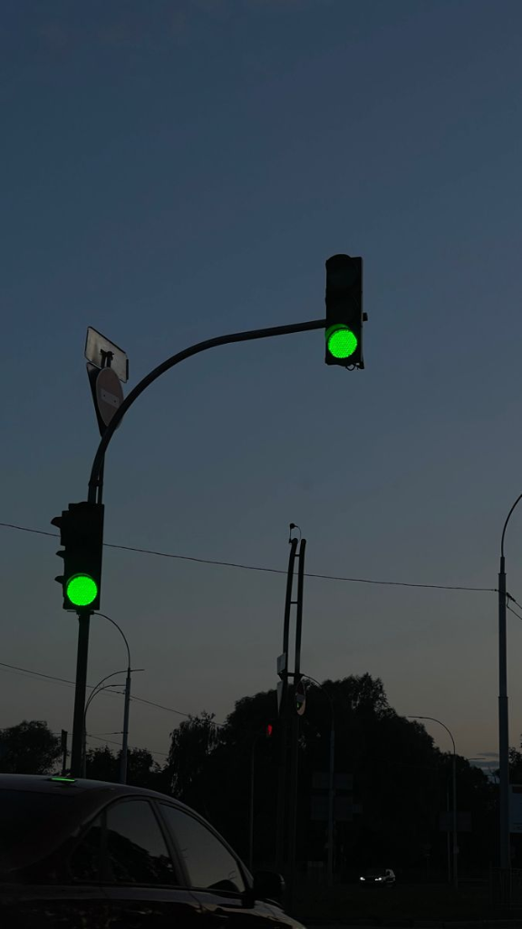 Glowing green traffic signal lights against twilight sky